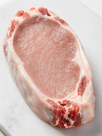 Свежие куски телятины светлого цвета со специями на деревянной разделочной доске